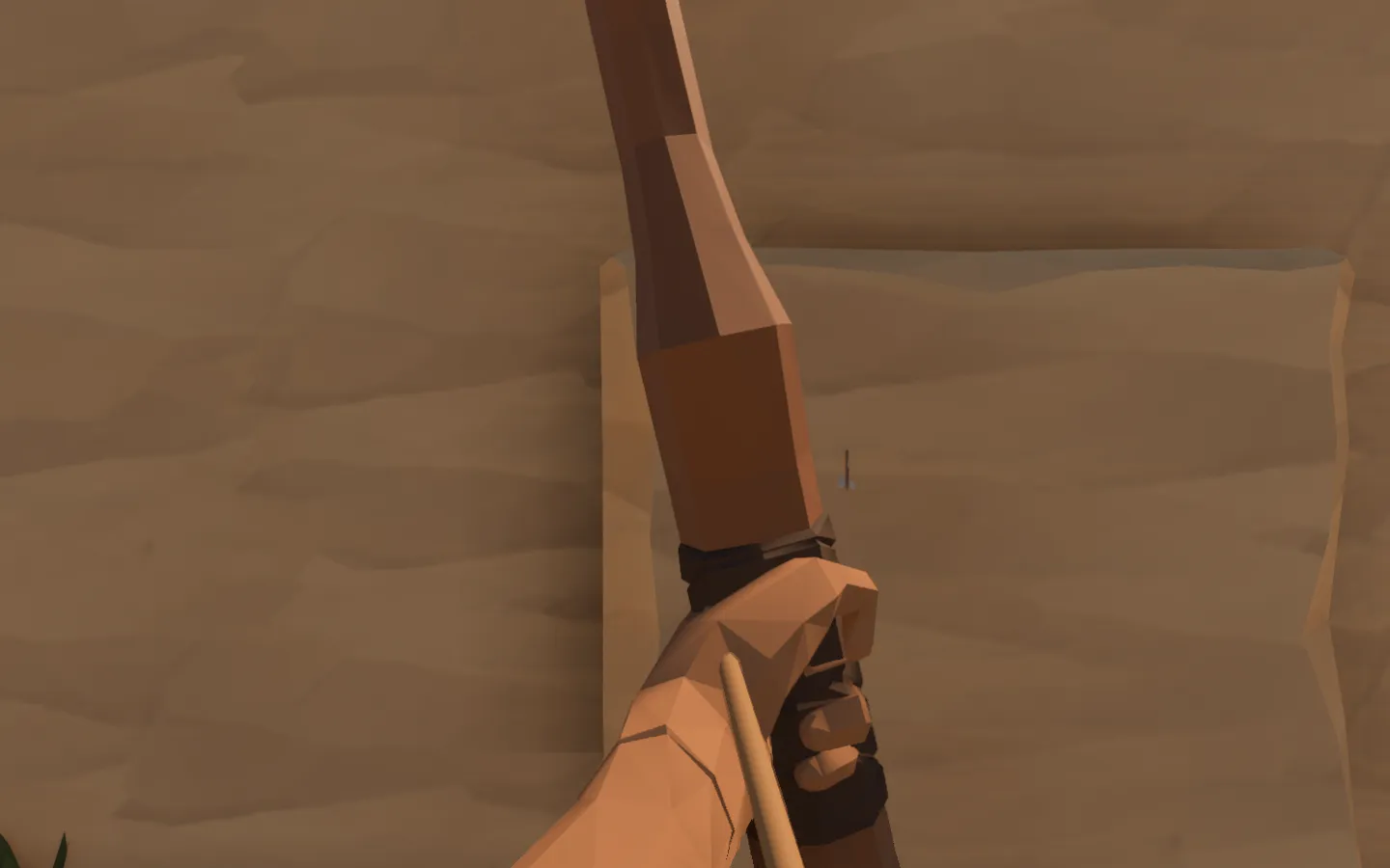 A first-person bow view close to a sandstone test wall, with a loosed arrow lodged in its face.