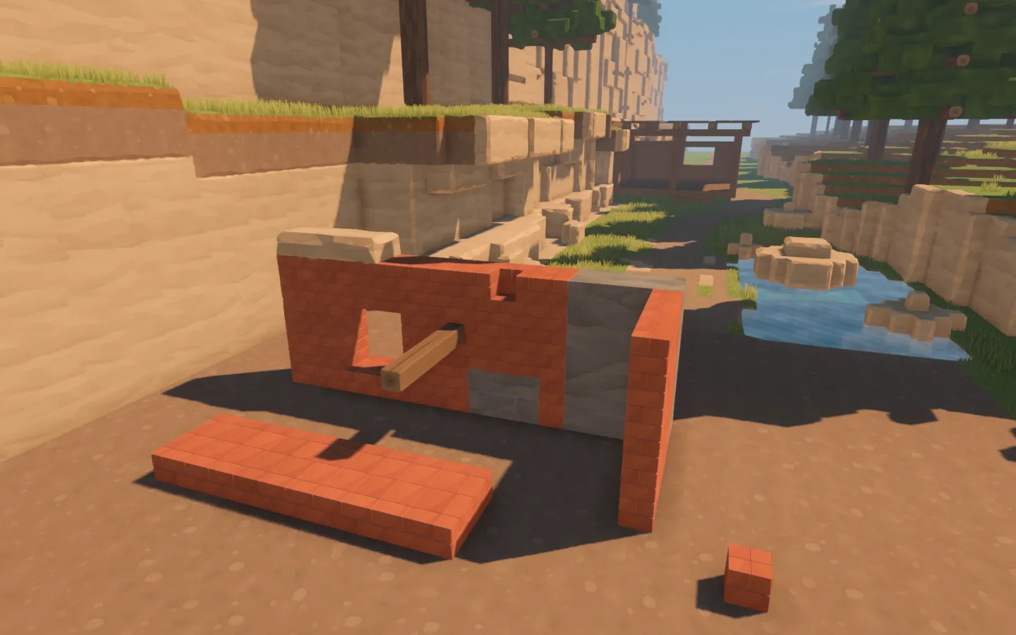 A clay brick test wall with a window opening, projecting timber beam, stone inserts and separate paving samples.