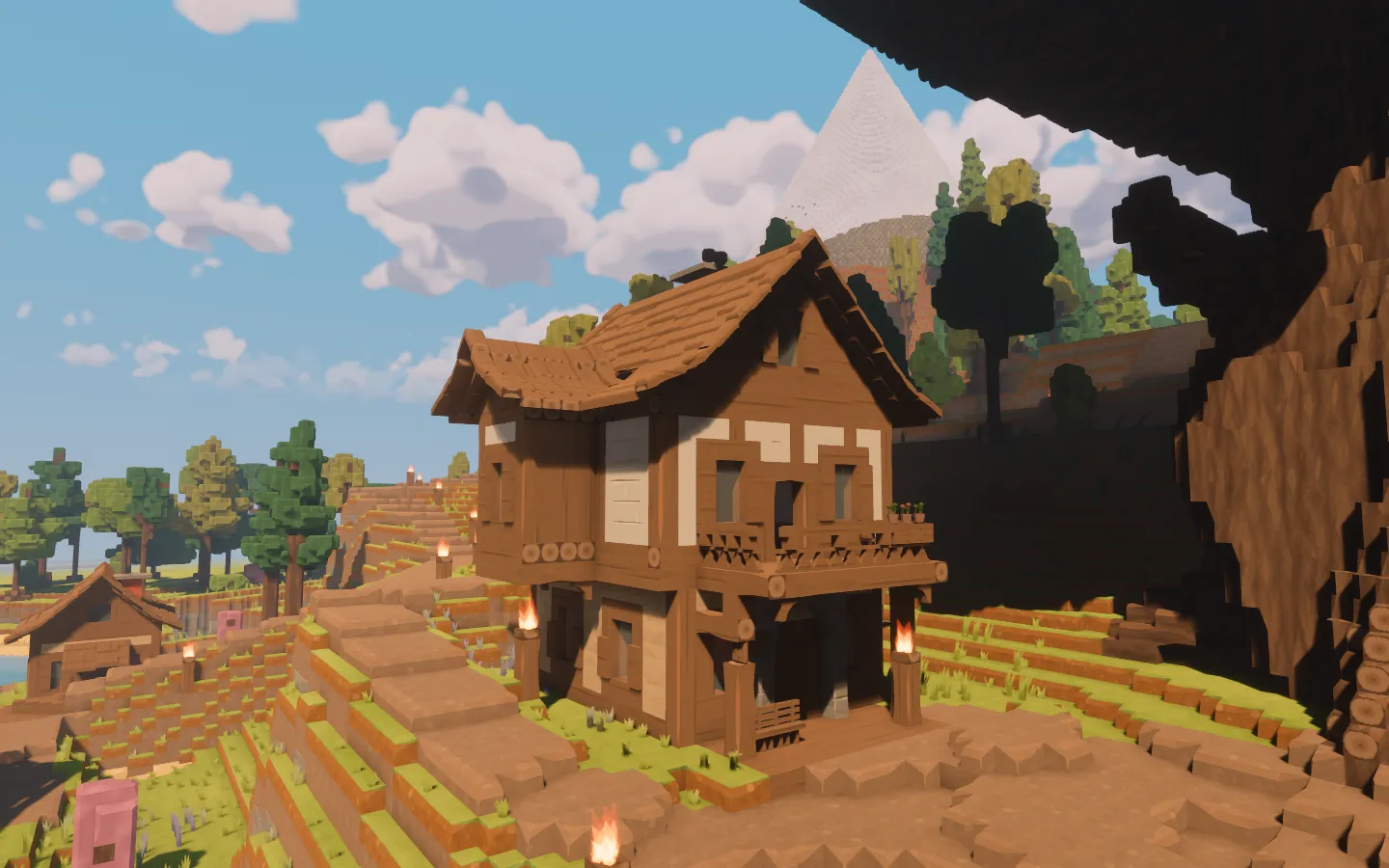 The timber-framed inn beneath the Hearth Tree, with a projecting upper floor, balcony, pale infill and a deep porch.