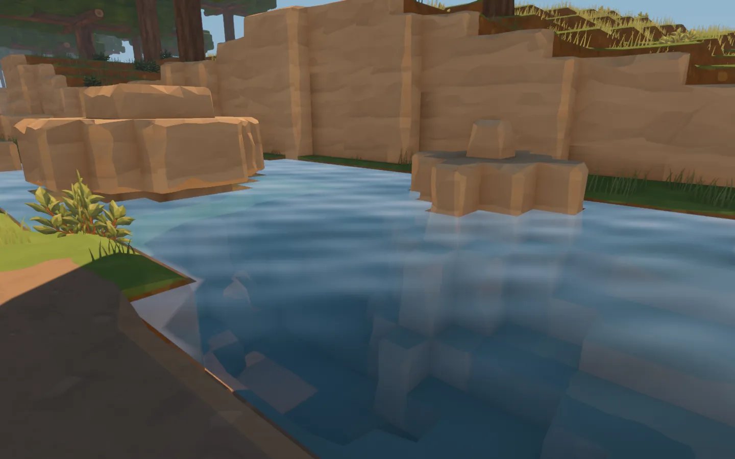 Clear blue water around sandstone outcrops, with a sandy shelf visible beneath the forest pool.